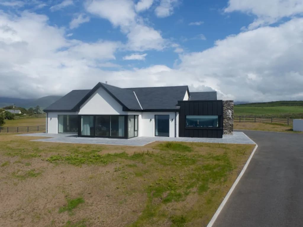 Contemporary house with black cladding and a stone chimney after the rebuild