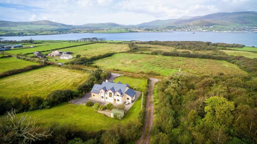 Aerial view of a house in fields beside a bay