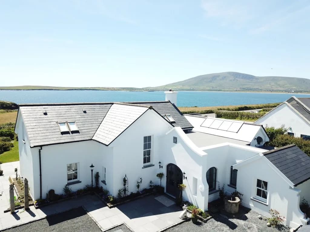 White house with a slate roof and courtyard, overlooking a bay
