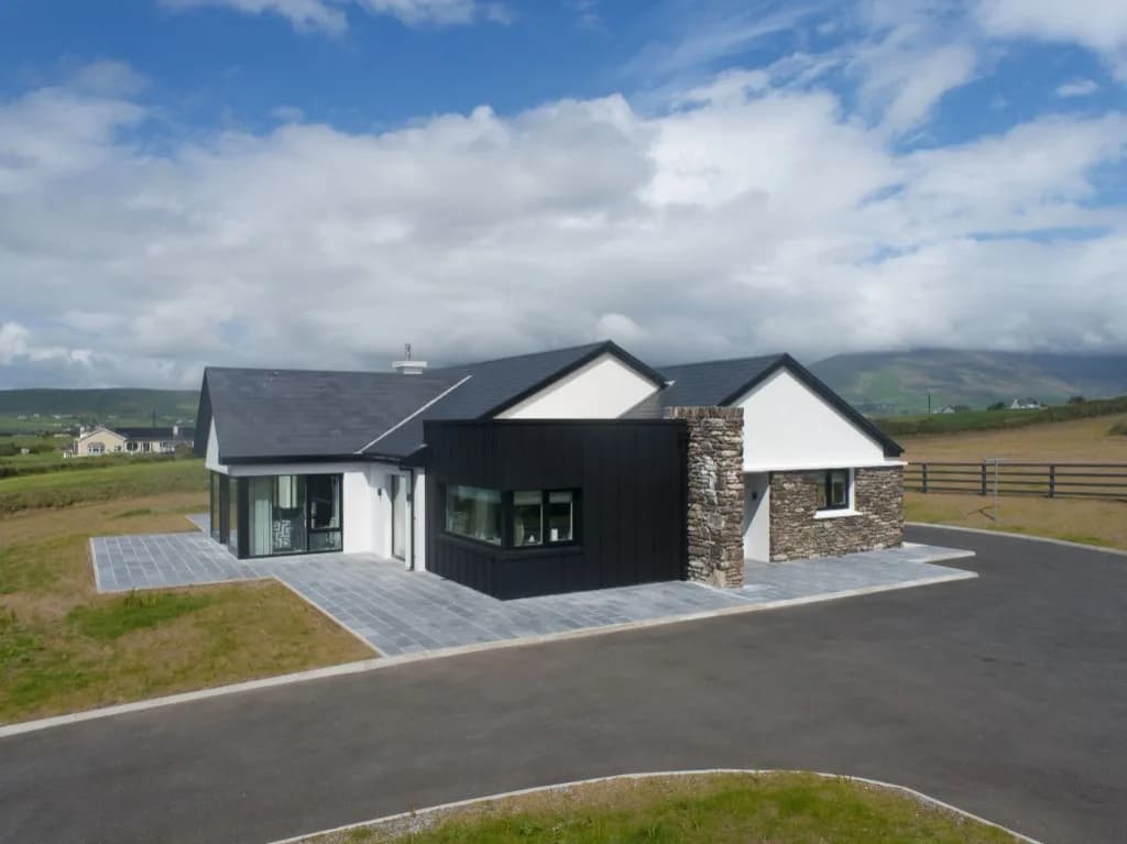 Contemporary house with black cladding, white render and a stone chimney