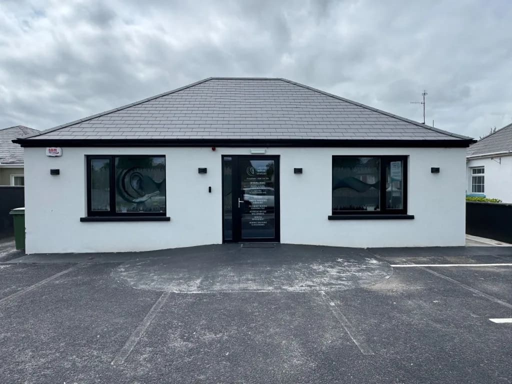 White commercial premises with a slate roof and glazed entrance